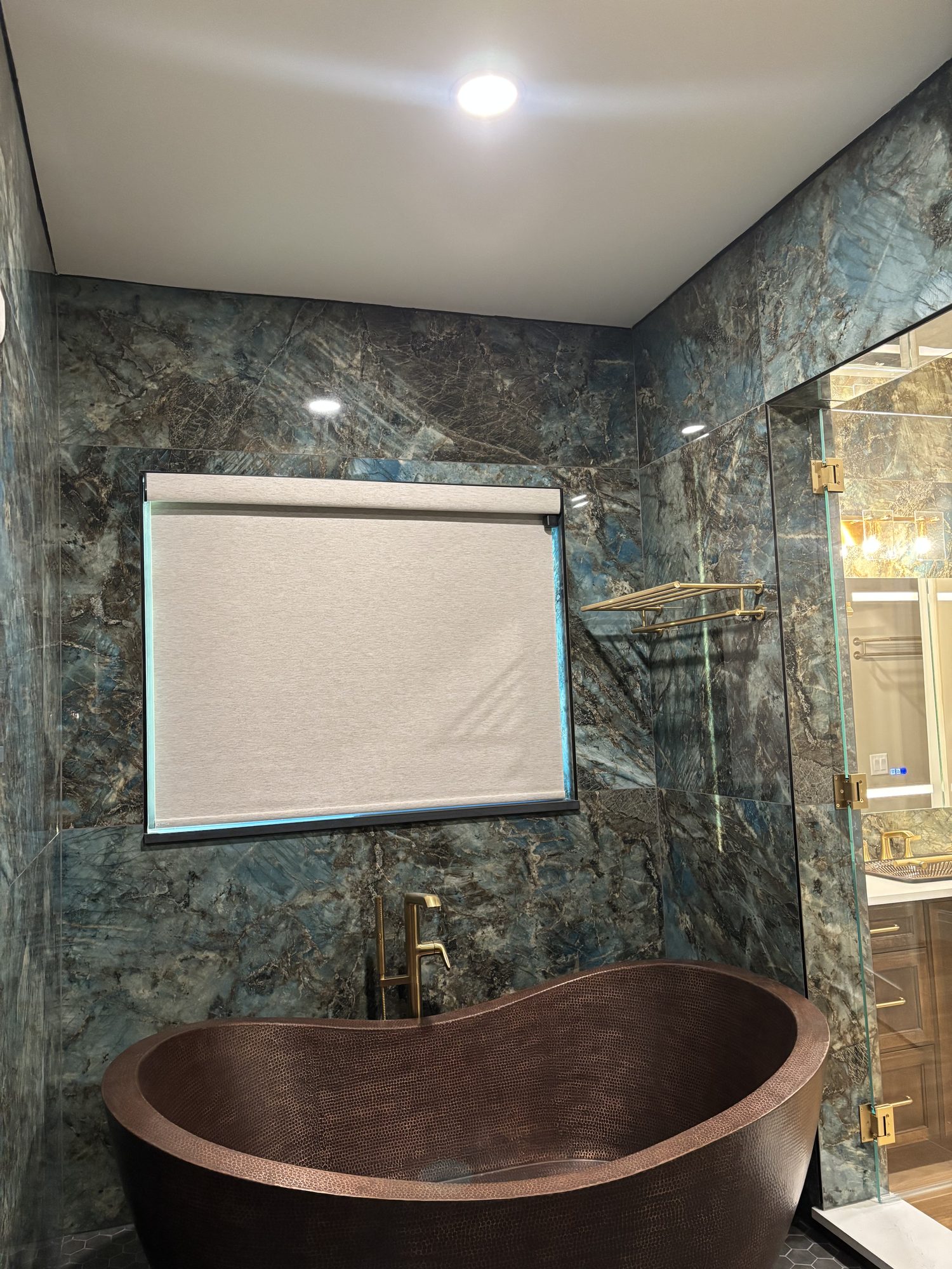Recessed lighting over copper soaking tub with motorised shade in Tampa waterfront custom home by Dim and Dimmer Electric