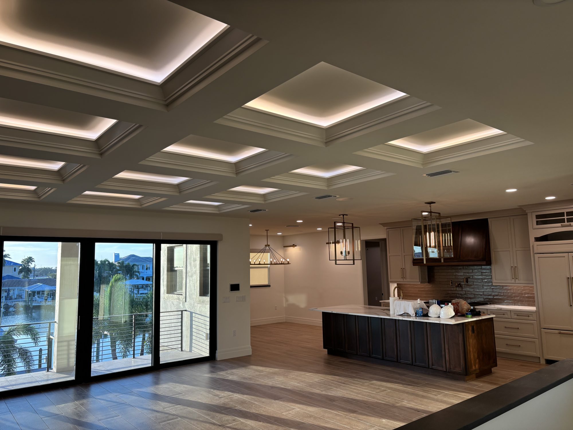 Coffered ceiling with cove LED lighting in open plan living and kitchen of Tampa waterfront custom home by Dim and Dimmer Electric
