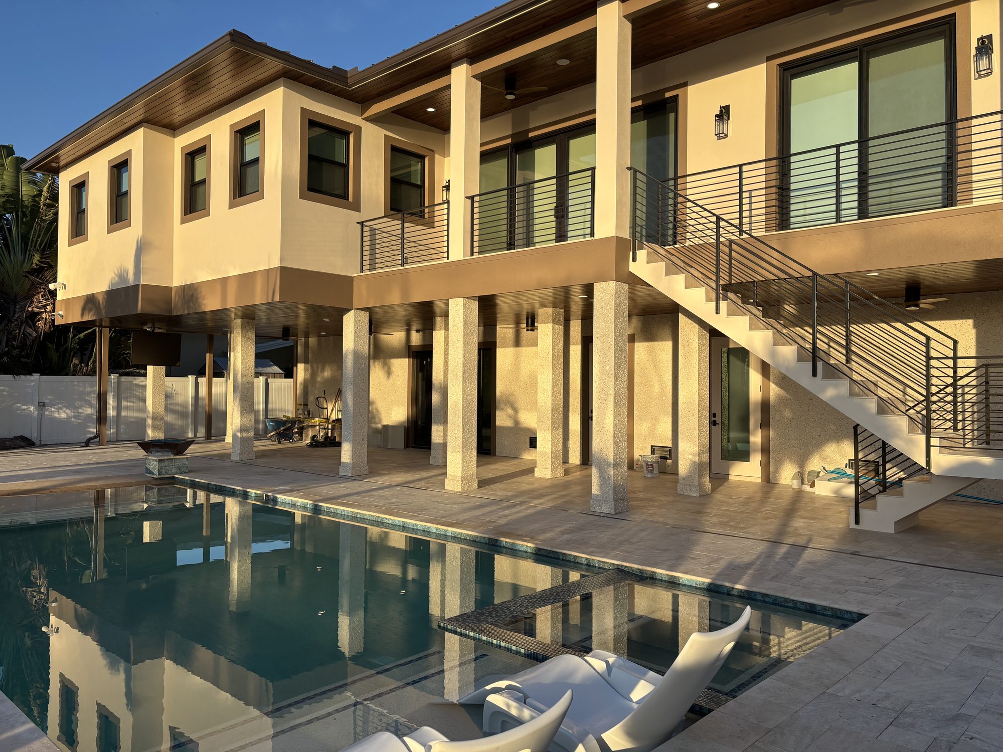 Rear exterior of elevated Tampa waterfront home with pool deck and sconce lighting by Dim and Dimmer Electric