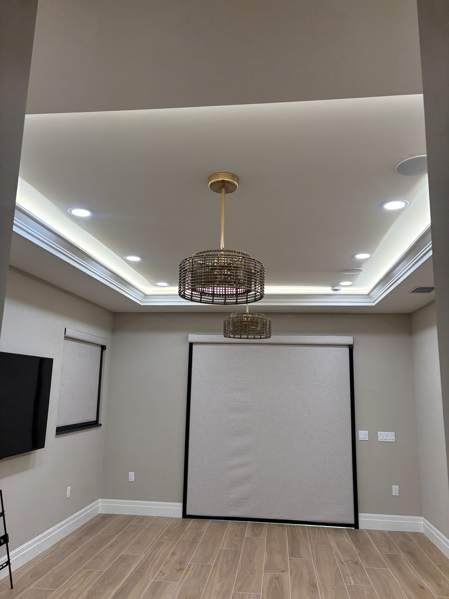 Tray ceiling cove lighting and pendant fixture in media room of Tampa custom home by Dim and Dimmer Electric