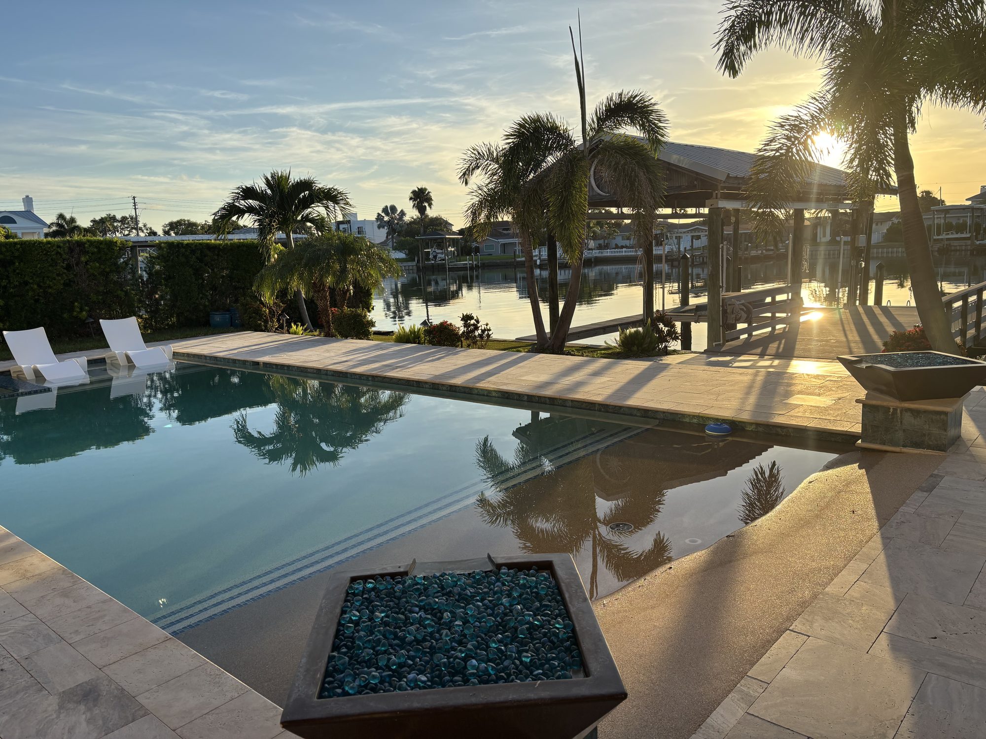 Waterfront pool deck and dock landscape lighting at sunset, custom home electrical build in Tampa by Dim and Dimmer Electric
